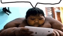 a very fat boy is holding a cell phone in his hand .