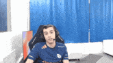 a man wearing headphones is sitting in a chair with a red bull shirt on