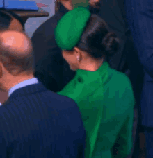 a man in a suit is shaking hands with a woman in a green hoodie .