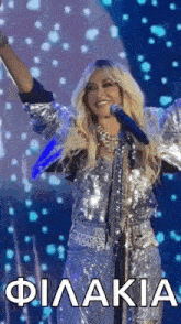 a woman is singing into a microphone on a stage while wearing a sequined jacket .