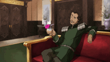 a man sits on a red couch holding a pink drink
