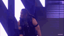 a wrestler is standing on a stage with a microphone in his hand .