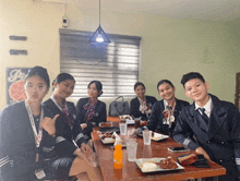 a group of people are sitting around a table with plates of food and drinks