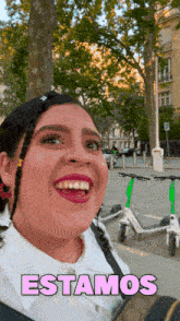 a woman is smiling in front of a sign that reads estamos