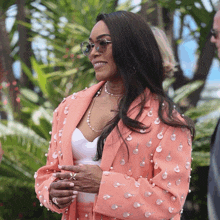 a woman wearing a pink suit with pearls on it