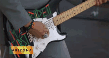 a man playing a guitar with arizona on the bottom right