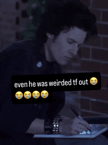 a man writing on a piece of paper with a sticker that says even he was weirded tf out