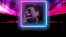 a man covering his face with his hands in a neon frame