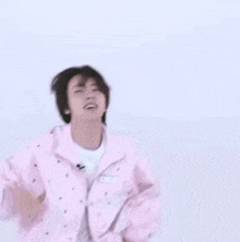 a young man is wearing a pink jacket and a white t-shirt .