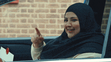 a woman in a hijab is giving a thumbs up