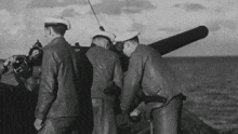 a black and white photo of three men standing around a cannon