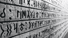 a black and white photo of a brick wall with foreign writing on it