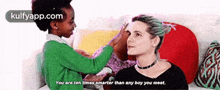a woman and a child are sitting on a couch and the child is putting something on the woman 's head .