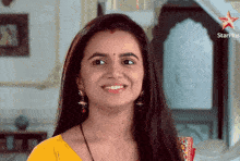 a woman in a yellow top is smiling in front of a starplus logo