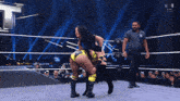 two women are wrestling in a wrestling ring with a referee in the corner