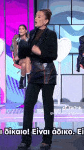 a woman in a black suit is dancing on a stage with a caption that says tiktok on it