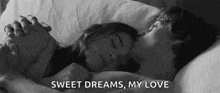 a black and white photo of a man and a woman sleeping in bed holding hands .
