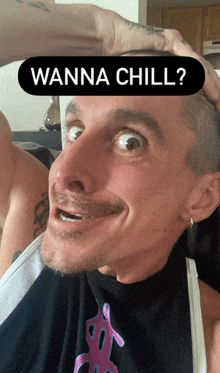 a man is making a funny face with a wanna chill sticker on his head