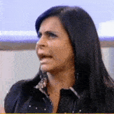 a woman with long black hair is making a funny face while talking on a television show .