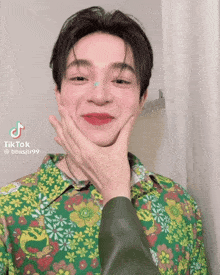 a man wearing a green shirt with flowers on it is making a funny face