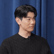 a man wearing a black sweater is laughing with his eyes closed and his mouth open