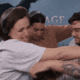 a group of people are hugging in front of a wall that says age