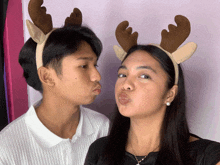 a man and a woman wearing reindeer antlers making funny faces