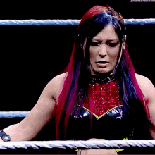 a woman with pink and blue hair is standing in a wrestling ring ..