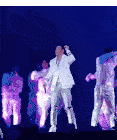 a man in a white suit is singing into a microphone