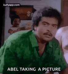 a man in a green shirt is taking a picture of himself in a room .