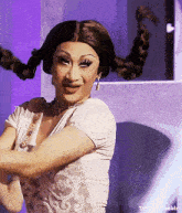 a drag queen with pigtails and a white top is dancing