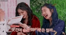 two girls are laughing while holding wine glasses