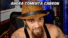 a man with a beard wearing a leopard print hat with the words ahora comenta cabron above him