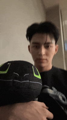 a man in a black shirt is holding a black hat