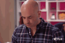 a man wearing a plaid shirt with netflix written on the bottom right