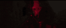 a close up of a person 's face in a dark room with a red light behind them .