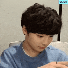 a young man wearing a blue shirt and a ring is sitting at a desk .