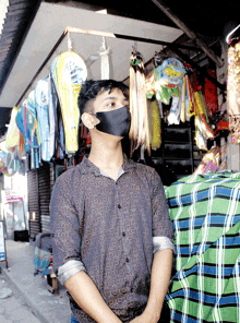a young man wearing a black mask stands in front of a store