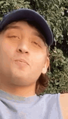 a close up of a man wearing a baseball cap and a gray shirt .