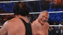 two men are wrestling in a ring and one has blood on his face