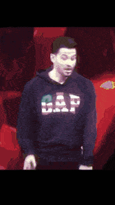a man wearing a gap hoodie is standing in front of a red background