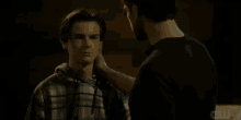 a man putting his hand on another man 's ear in a dark room