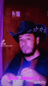 a man wearing a cowboy hat is holding a piece of paper that says que what 's