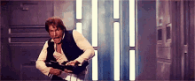 han solo is holding a gun in a room with a door .