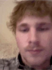 a close up of a man 's face with a plaid shirt on