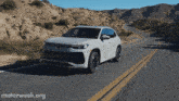 a white suv is driving down a desert road with motorweek.org written on the bottom
