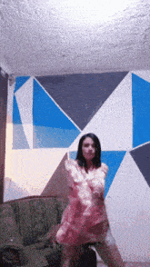 a woman in a pink dress is dancing in front of a couch