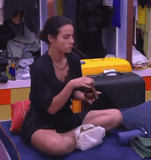 a woman is sitting on a bed with her legs crossed and holding a bag .