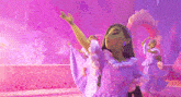 a woman in a purple dress is dancing in front of a pink wall .