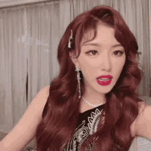 a woman with red hair is wearing a black top and earrings